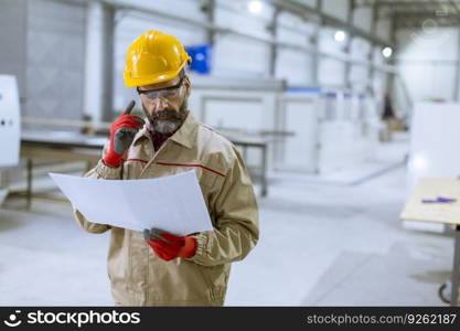 Handsome mature engineer looking at a plan in the factory