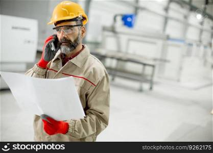 Handsome mature engineer looking at plan in the factory