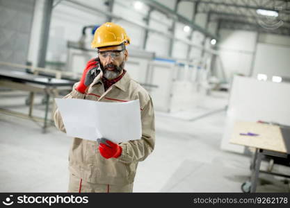 Handsome mature engineer looking at plan in the factory