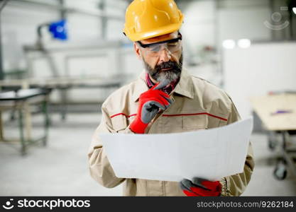 Handsome mature engineer looking at plan in the factory