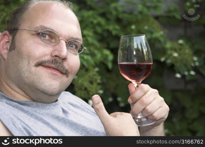 Handsome mature man enjoying a glass of rose in the garden