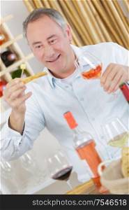 handsome mature man tasting glass of rose wine