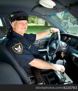 Handsome mature police officer driving his squad car.