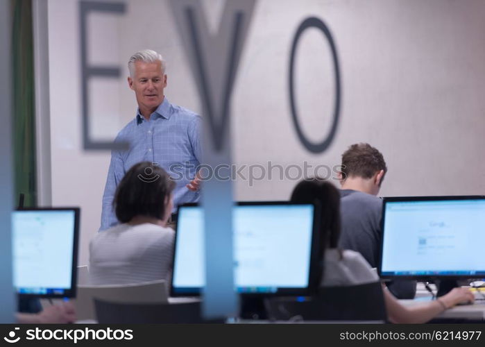 handsome mature teacher and students in computer lab classroom