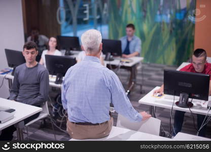 handsome mature teacher and students in computer lab classroom