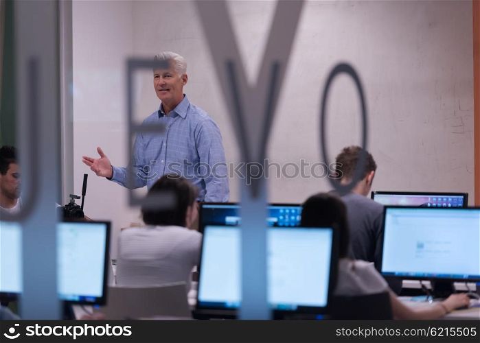 handsome mature teacher and students in computer lab classroom