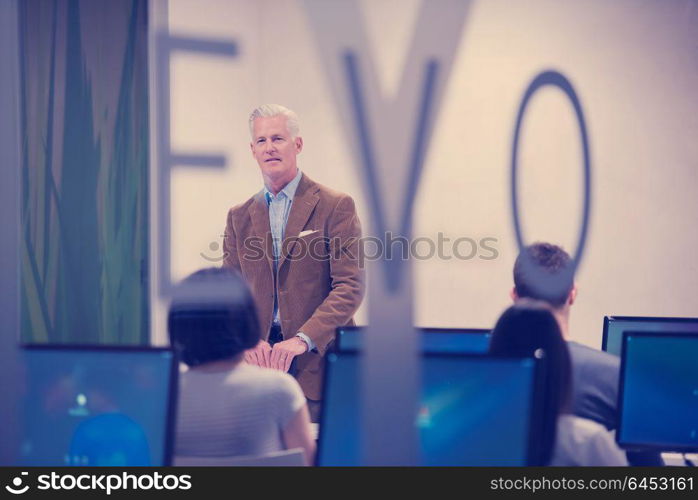 handsome mature teacher and students in computer lab classroom