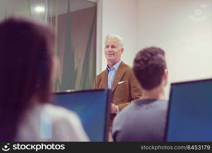 handsome mature teacher and students in computer lab classroom
