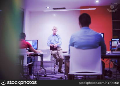 handsome mature teacher and students in computer lab classroom