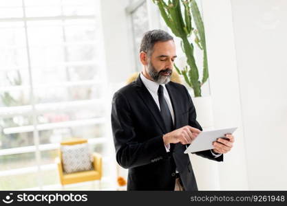 Handsome middle age businessman with digital tablet in the modren office