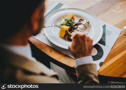 Handsome middle-aged businessman having lunch in restaurant