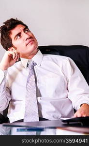 handsome middle aged businessman is sitting in chair at his cabinet