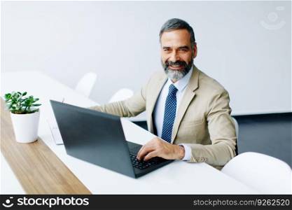 Handsome middle-aged businessman working on laptop in modern office