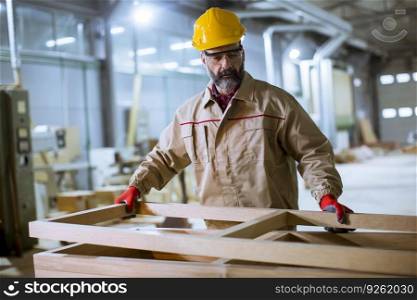 Handsome middle aged worker in protective clothes working in the furniture factory
