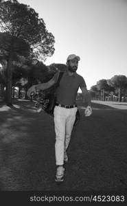 handsome middle eastern golf player carrying and bag and walking at course on beautiful morning sunrise