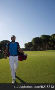 handsome middle eastern golf player carrying and bag and walking at course on beautiful morning sunrise