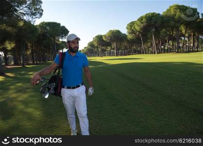 handsome middle eastern golf player carrying and bag and walking at course on beautiful morning sunrise