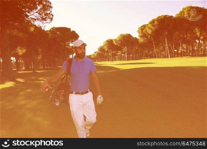 handsome middle eastern golf player carrying and bag and walking at course on beautiful morning sunrise. golf player walking