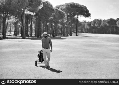 handsome middle eastern golf player carrying and bag and walking at course on beautiful sunset