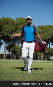 handsome middle eastern golf player carrying bag and walking at course to next hole