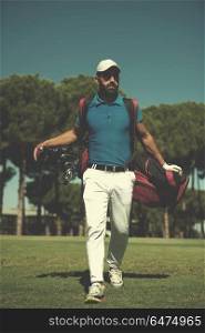 handsome middle eastern golf player carrying bag and walking at course to next hole. golf player walking and carrying bag