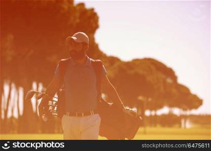 handsome middle eastern golf player carrying bag and walking at course to next hole. golf player walking and carrying bag