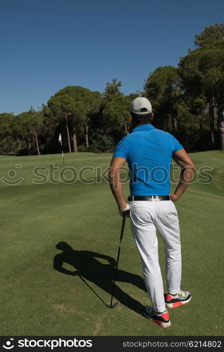 handsome middle eastern golf player portrait from back with course in background at beautiful sunny day