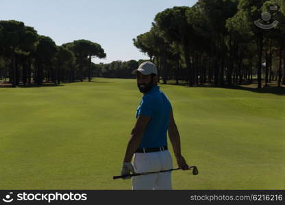handsome middle eastern golf player portrait from back with course in background at beautiful sunny day