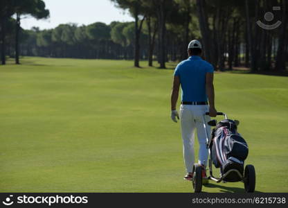 handsome middle eastern golf playerwalking with wheel bag at course on beautiful sunny day