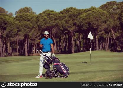 handsome middle eastern golf playerwalking with wheel bag at course on beautiful sunny day. golf player walking with wheel bag