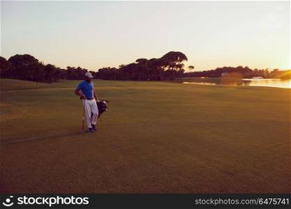 handsome middle eastern golfer carrying bag and walking to next hole at golf course on beautiful sunset in background. golfer walking and carrying golf bag at beautiful sunset