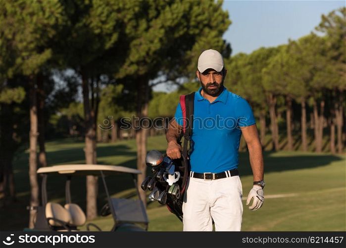 handsome middle eastern golfer carrying bag and walking to next hole at golf course
