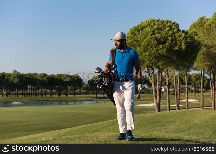 handsome middle eastern golfer carrying bag and walking to next hole at golf course