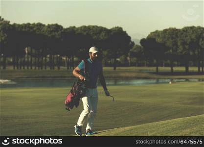 handsome middle eastern golfer carrying bag and walking to next hole at golf course. golfer walking and carrying bag