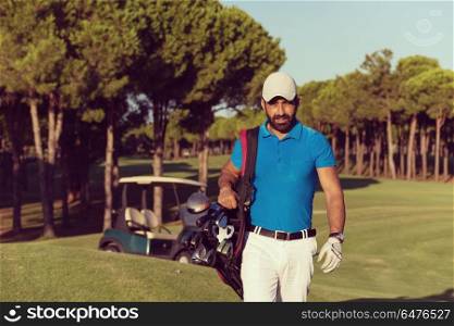 handsome middle eastern golfer carrying bag and walking to next hole at golf course. golfer walking and carrying golf bag
