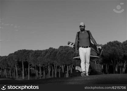 handsome middle eastern golfer carrying golf bag and walking at course to next hole