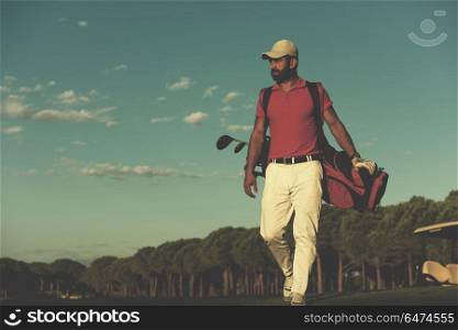 handsome middle eastern golfer carrying golf bag and walking at course to next hole. golfer walking and carrying golf bag