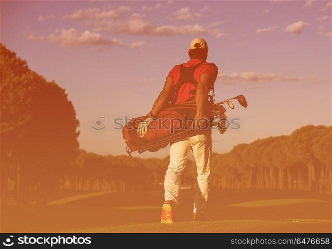 handsome middle eastern golfer carrying golf bag and walking at course to next hole. golfer walking and carrying golf bag