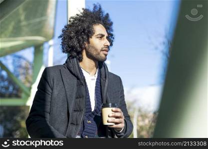 Handsome modern afro man with beard smiling positive standing at the street drinking a take away cup of coffee