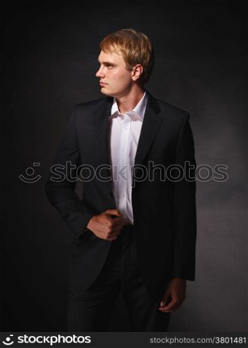 Handsome modern businessman wearing black suit, studio shot dark background