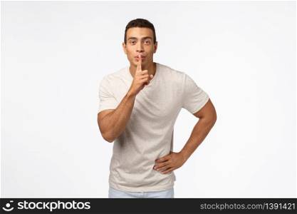 Handsome muscular boyfriend in casual t-shirt, prepare surprise for valentines day, shushing, making hush sound as press index finger to lips and smile, have secret, standing white background.. Handsome muscular boyfriend in casual t-shirt, prepare surprise for valentines day, shushing, making hush sound as press index finger to lips and smile, have secret, standing white background