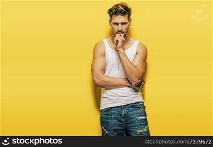 Handsome, muscular guy posing on a yellow background