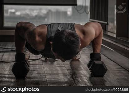 Handsome muscular man doing pushups on dumbbell in gym or fitness club. Healthy lifestyle bodybuilding, Athlete builder muscles lifestyle.