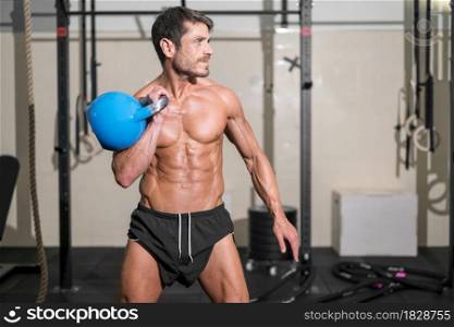 Handsome muscular man lifting heavy kettlebell. High quality photo.. Handsome muscular man lifting heavy kettlebell