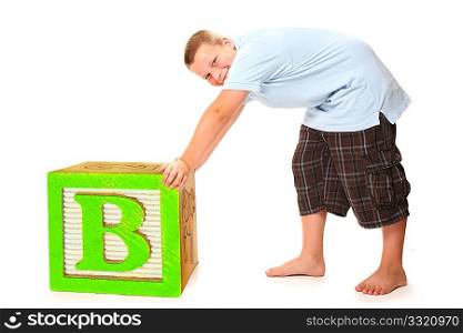 Handsome nine year old boy pushing giant alphabet block over white.