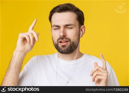 Handsome of a young man enjoying music over yellow background. Handsome of a young man enjoying music over yellow background.