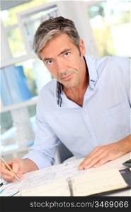 Handsome office worker writing notes on agenda