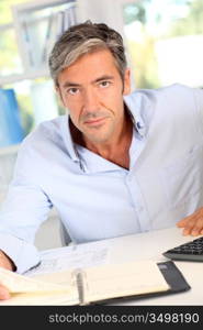 Handsome office worker writing notes on agenda