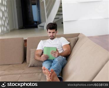 Handsome relaxed young businessman working from home on tablet computer