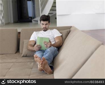 Handsome relaxed young businessman working from home on tablet computer